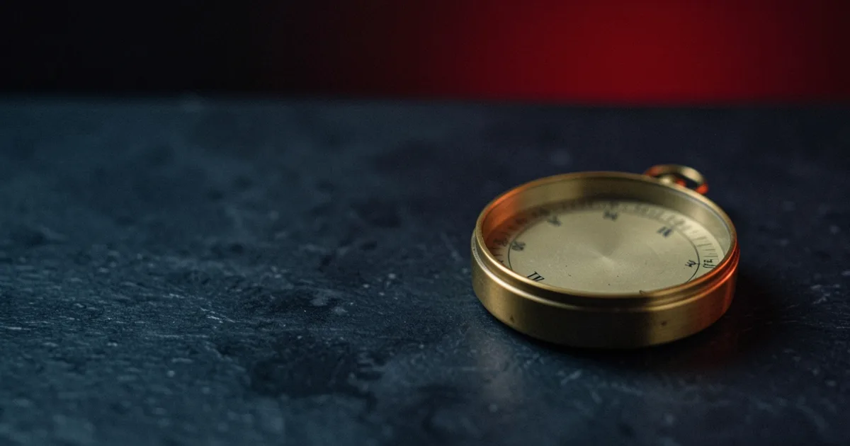 A brass compass lying on a dark stone table under a red light